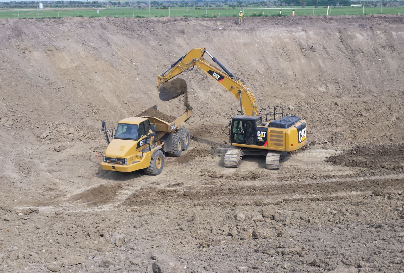 Excavator dumping dirt into a dump truck